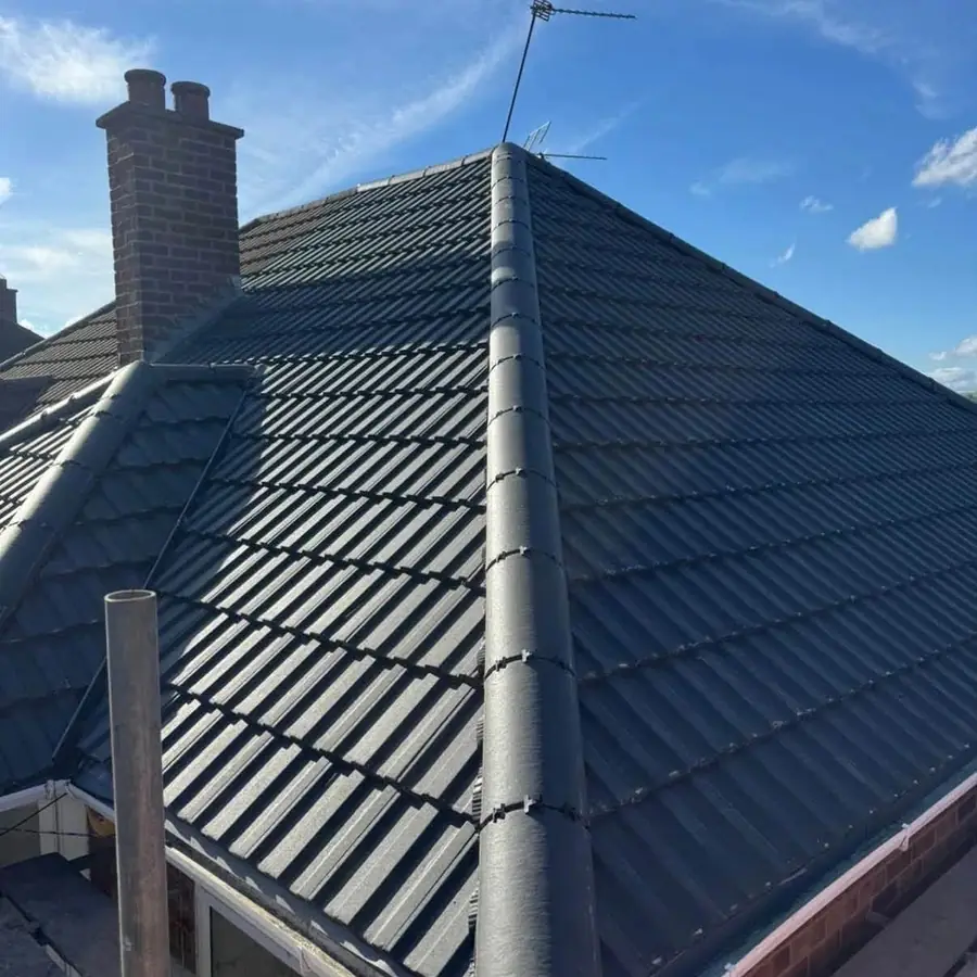 Finished dark tile hip roof with dry hips and a chimney